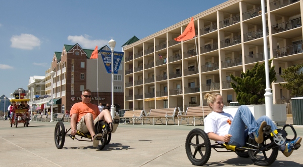 Beachgoers wheel their way down Ocean City's boardwalk with some of the city's hotels in the background. (File Photo)