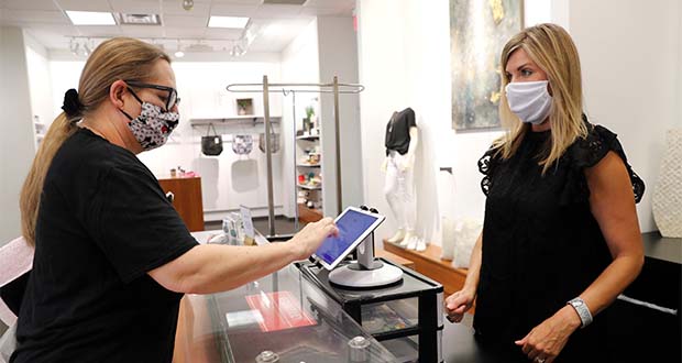 FILE In this Wednesday, May 13, 2020 FILE photo, Monique Kursar, left, completes a purchase with Amy Witt, owner of the Velvet Window, in Dallas. For small retailers across the country, the coronavirus outbreak has turned an already challenging business environment into never-ending uncertainty. Witt might have 20 customers on a good day in her women’s clothing store, and then none the next. “It’s a rollercoaster we ride every day,” says Witt (AP Photo/LM Otero)