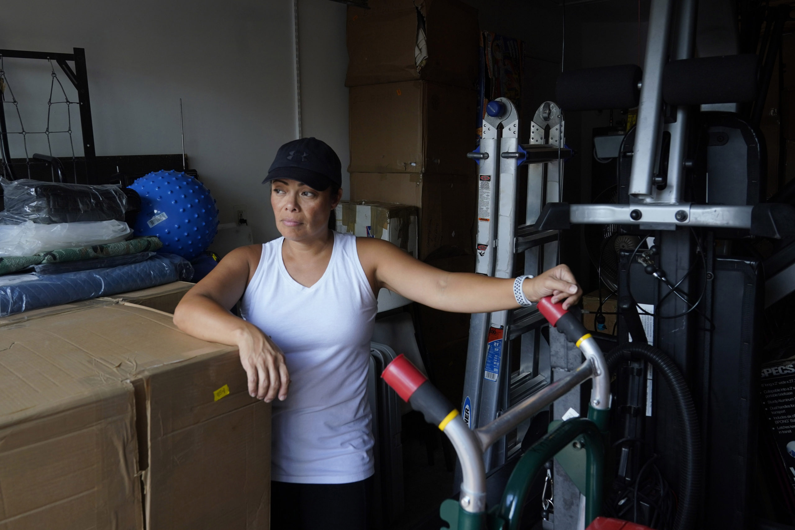 Wendy Kaufman stands at the entrance to her packed garage April 12, 2022, in Doral, Florida. The Kaufmans moved from Germany and have been unable to find a home big enough that they can afford. (AP Photo/Marta Lavandier)