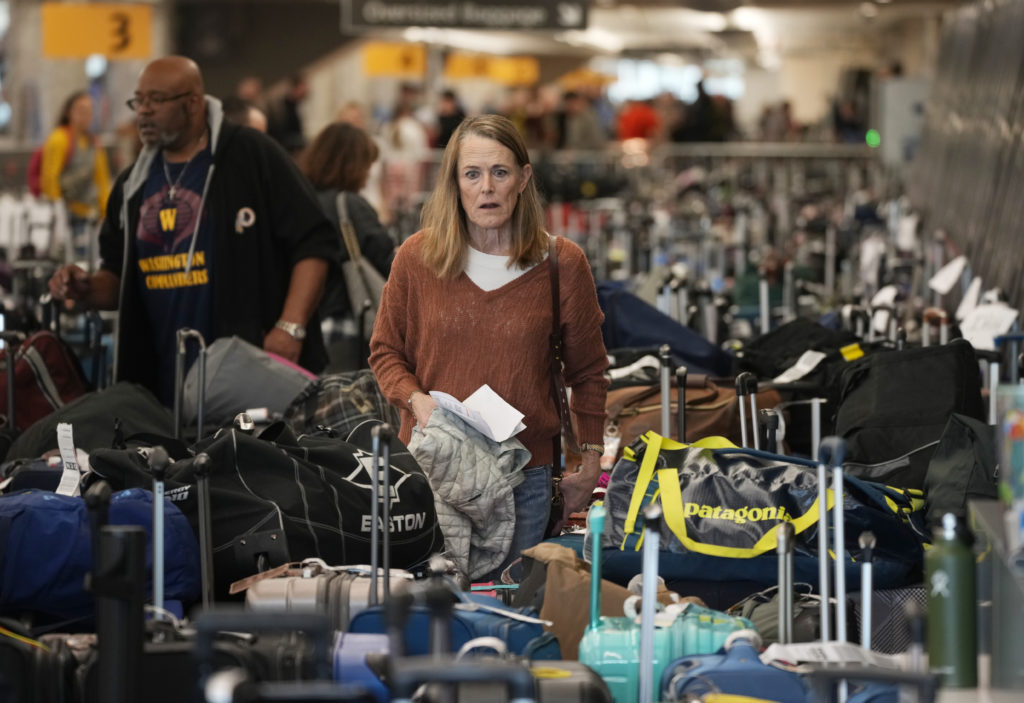 A traveler wades through the field of unclaimed bags at the Southwest Airlines luggage carousels at Denver International Airport on Dec. 27, 2022. (AP Photo/David Zalubowski)