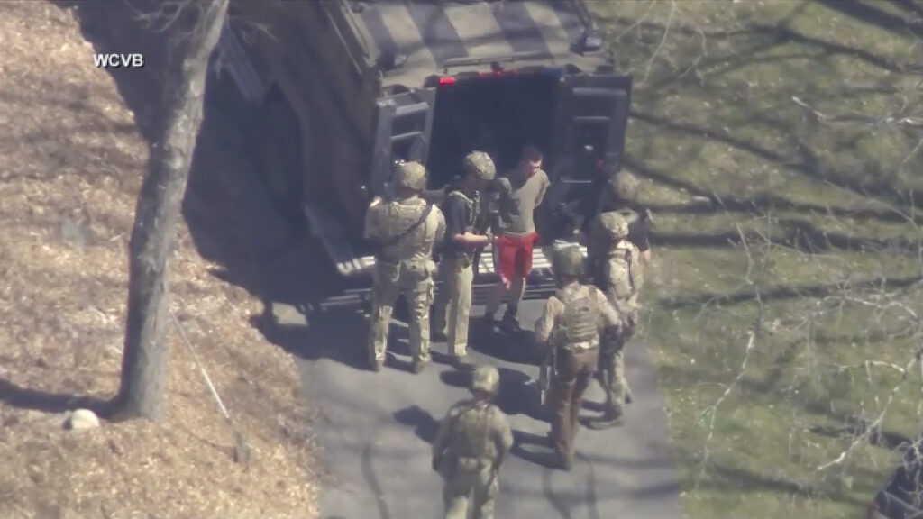 This image made from video provided by WCVB-TV, shows Jack Teixeira, in T-shirt and shorts, being taken into custody by armed tactical agents on April 13, 2023, in Dighton, Massachusetts. (WCVB-TV via AP)
