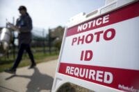A Super Tuesday voter walks past a sign requiring a photo ID at a polling location in Mount Holly, North Carolina, on March 5, 2024. A federal lawsuit challenging North Carolina's photo voter identification law goes to trial Monday, May 6, with expected arguments focusing on whether the requirement unlawfully discriminates against Black and Hispanic citizens or serves legitimate state interests to boost public confidence in elections. (AP Photo/Chris Carlson, File)