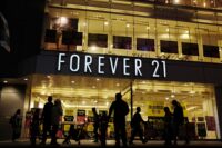 Shoppers walk by a Forever 21 clothing store in Tokyo on Oct. 24, 2019, as the liquidation sale signs are posted on the storefront. (AP Photo/Kiichiro Sato, file)