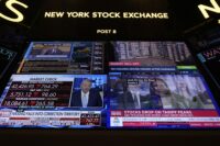 Financial news is displayed as people work on the floor at the New York Stock Exchange in New York on March 4, 2025. (AP Photo/Seth Wenig)