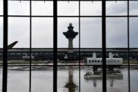 A mobile lounge rolls along in front of the old air-traffic control tower at Washington Dulles International Airport in 2019. (Katherine Frey/The Washington Post)