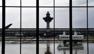 A mobile lounge rolls along in front of the old air-traffic control tower at Washington Dulles International Airport in 2019. (Katherine Frey/The Washington Post)