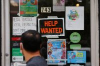 A pedestrian passes a "Help Wanted" sign in the door of a hardware store in Cambridge, Massachusetts, on July 8, 2022. (REUTERS/Brian Snyder/File Photo)