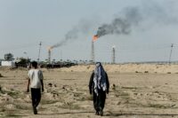 People walk near farmland by the Zubair oil field as gas flares rise in the distance, in Zubair Mishrif, Basra, Iraq, amid regional tensions following the recent disruption to shipping in the Strait of Hormuz and the U.S.-Israeli conflict with Iran, on March 9, 2026. (REUTERS/Essam al-Sudani/File Photo)