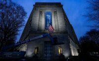 A new banner depicting President Donald Trump is put up on the Department of Justice building in Washington on Feb. 20, 2026. (REUTERS/Ken Cedeno)