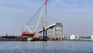 Two years after the Francis Scott Key Bridge collapsed, the Weeks 533 crane drives a pile beneath the Patapsco River on the site of a new bridge. (Dan Belson/The Daily Record)
