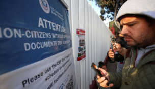 Migrants check their phones while gathering at El Chaparral border crossing after their CBP One app asylum appointment was cancelled on the day of President Donald Trump's inauguration, in Tijuana, Mexico January 20, 2025. (REUTERS/Jorge Duenes)