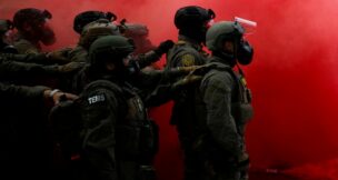 Law enforcement officers stand amid smoke from a smoke grenade released to disperse demonstrators in front of the U.S. Immigration and Customs Enforcement (ICE) headquarters in Portland, Oregon, on Oct. 4, 2025. (REUTERS/Carlos Barria)