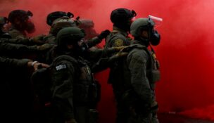 Law enforcement officers stand amid smoke from a smoke grenade released to disperse demonstrators in front of the U.S. Immigration and Customs Enforcement (ICE) headquarters in Portland, Oregon, on Oct. 4, 2025. (REUTERS/Carlos Barria)