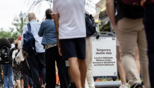 Commuters wait in line July 7, 2026, for shuttle buses outside the Friendship Heights station. (Christine Kao/The Washington Post)