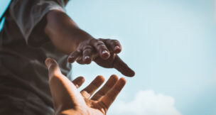 Help Concept hands reaching out to help each other in dark tone.