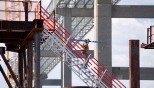 A construction worker descends a stairway Wednesday at the construction site for the replacement Francis Scott Key Bridge. Crews are continuing to drive piles into the Patapsco riverbed for the new bridge as the state seeks new contractors for the bridge's construction. (Photo by Christine Condon/Maryland Matters)