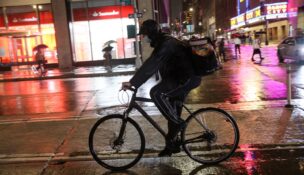 A food delivery rider rides a bicycle through the rain during a delivery in midtown Manhattan, New York, on Sept. 23, 2021. (REUTERS/Angus Mordant/File Photo)