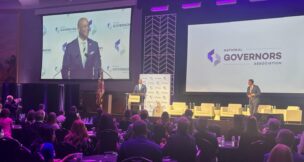 Maryland Gov. Wes Moore (D), at podium, takes over the National Governors Association chairmanship from from Oklahoma Gov. Kevin Stitt (R), right, on Aug. 1, 2026. Chairmanship of the bipartisan organization shifts between parties every year. (Photo by Kevin Hardy/Stateline)