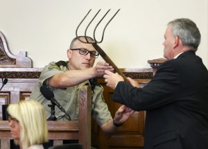 Delaware County's county attorney John Bernau, right, questions witness Delaware County Deputy Eric Holub as he hands back a corn rake during the first-degree murder trial for Todd Mullis at Dubuque County Courthouse in Dubuque, Iowa, on Tuesday, Sept. 17, 2019. Todd Mullis is accused of killing Amy L. Mullis by stabbing her with that rake on Nov. 10. (Nicki Kohl/Telegraph Herald via AP)